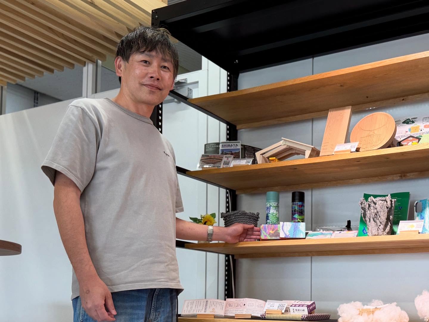 作品が並ぶ棚の前に立つ津嶋勇士さん