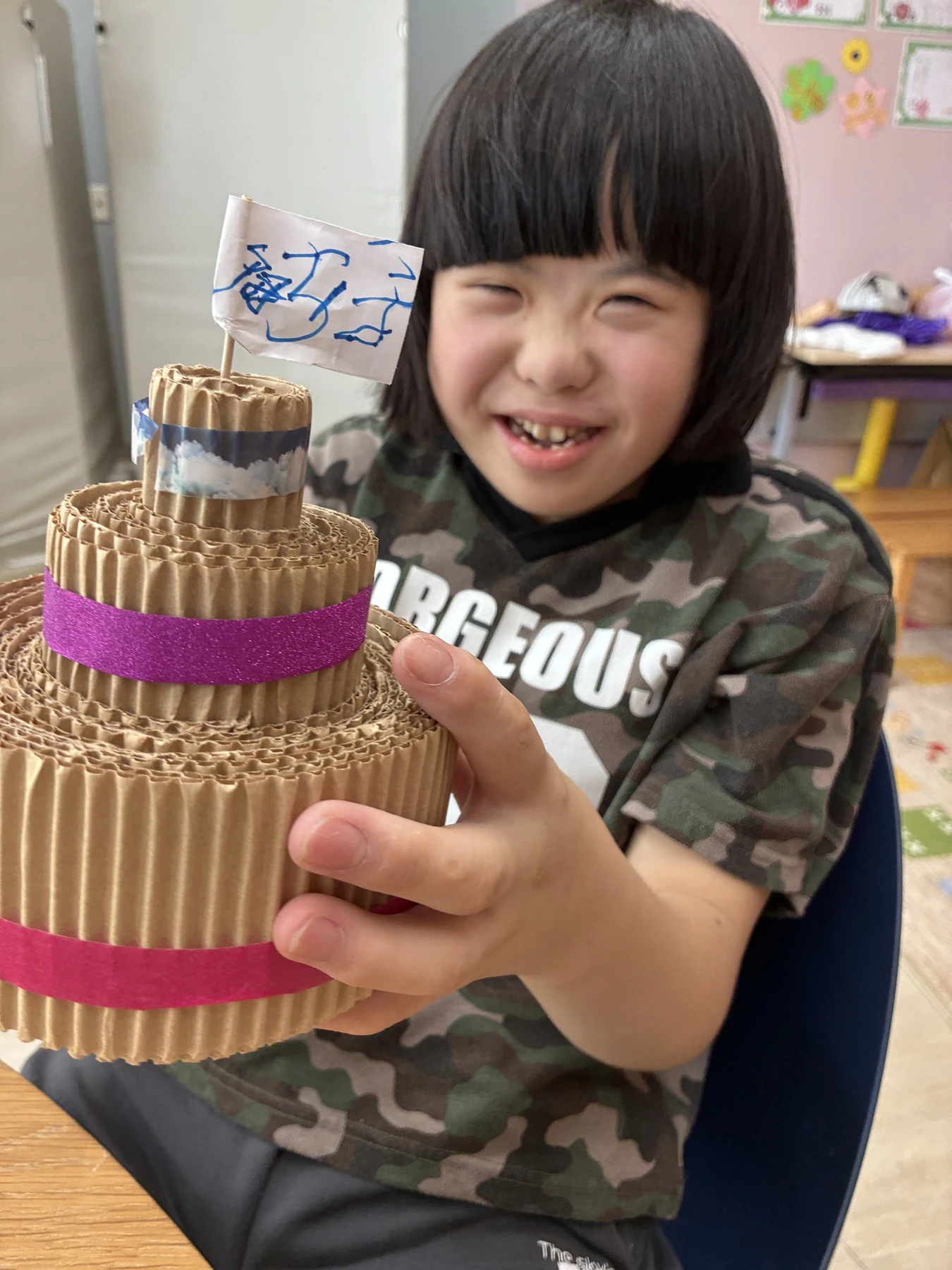 木の実でつくったケーキを手に、笑顔を見せる子ども